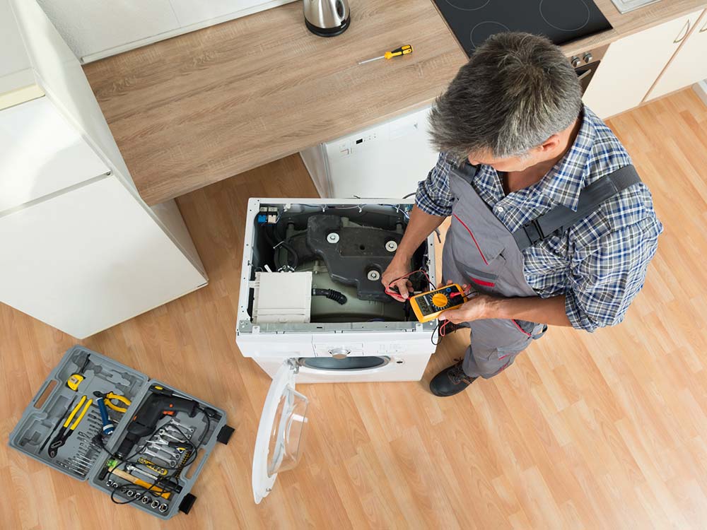 Hombre realizando reparación a lavadora